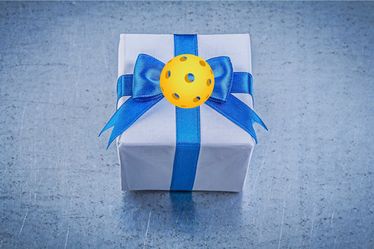 Wrapped gift box with blue ribbon showing pickleball on top of bow