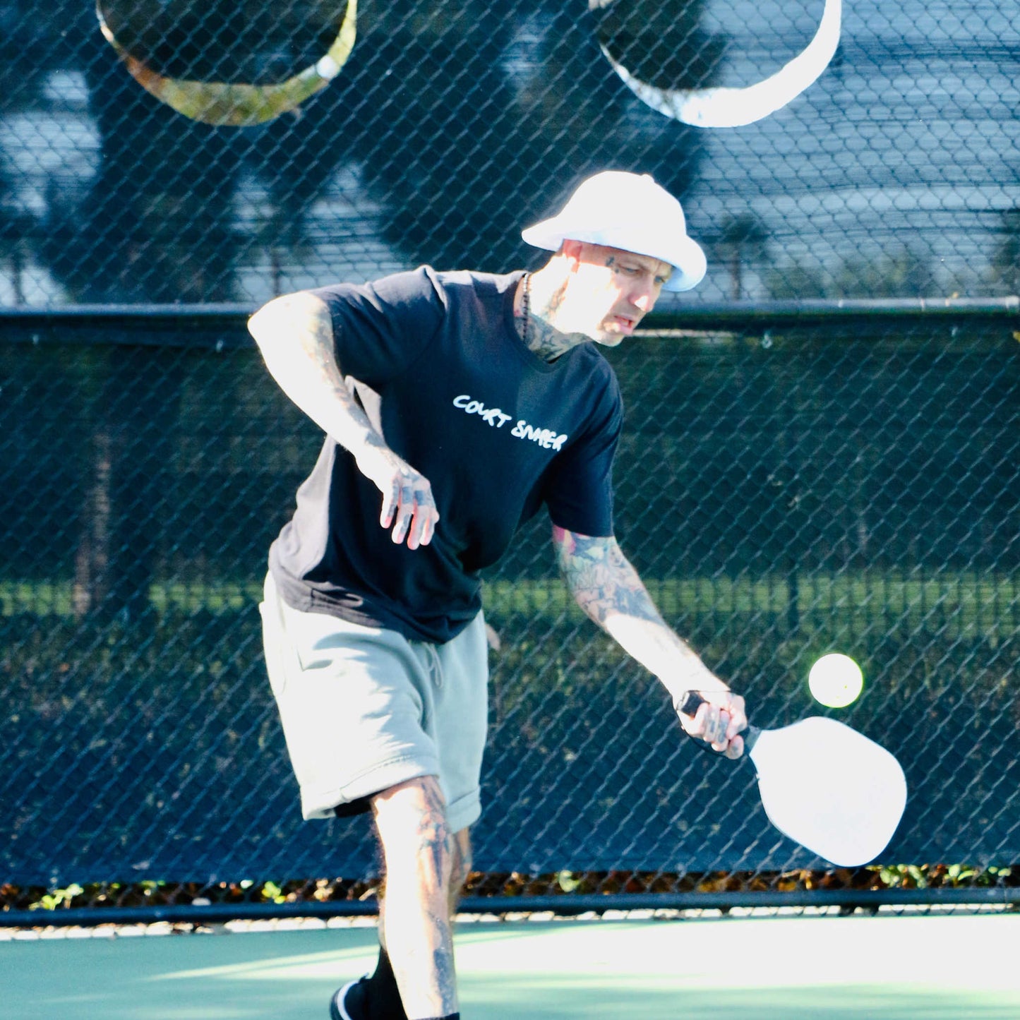 Pickleball player hitting a ball on court wearing Court Sniper shirt from Soul Bandit Pickleball.